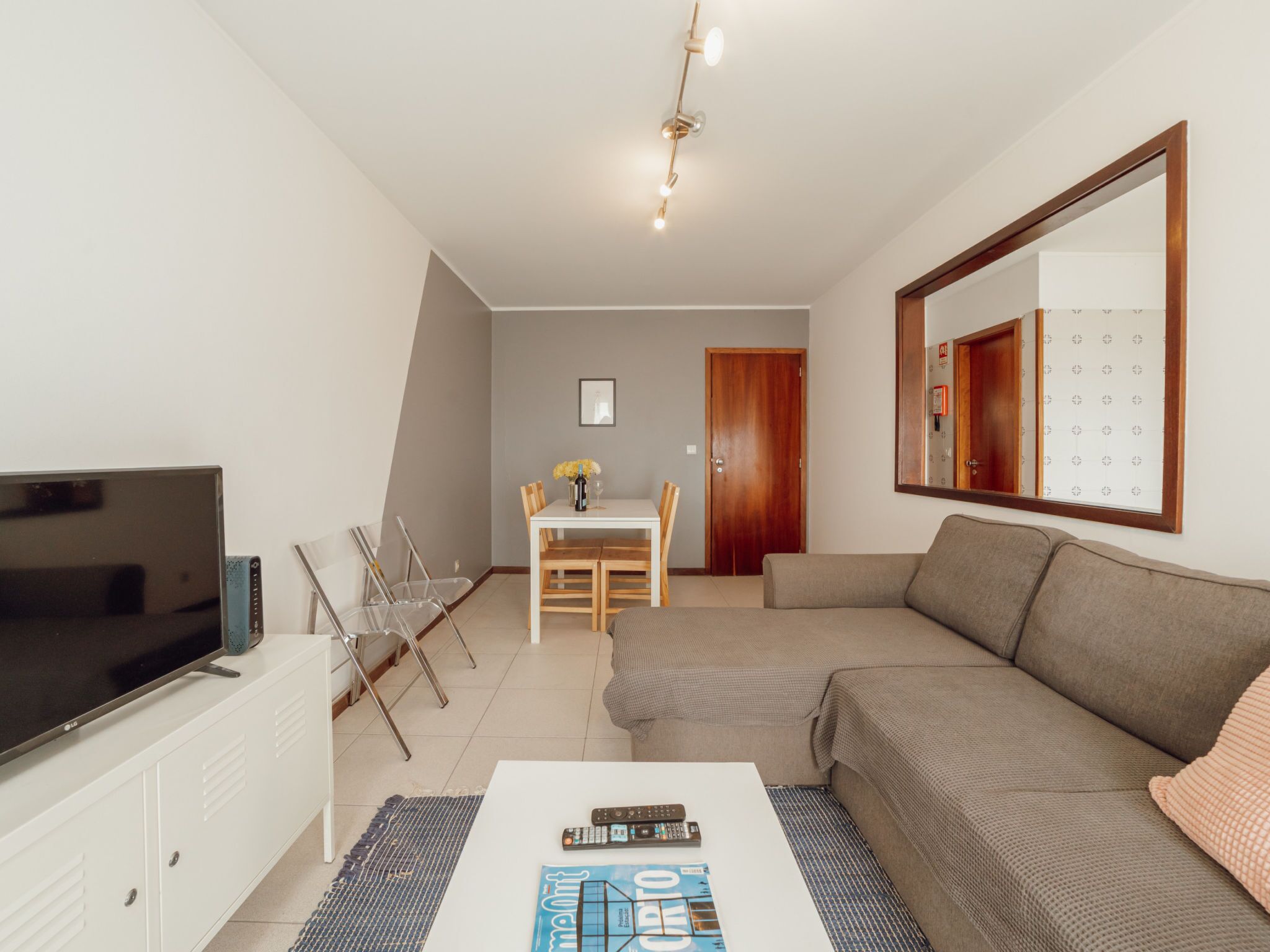 Un salon comprenant un téléviseur, un canapé, une table basse et un coin repas avec des chaises et une table.