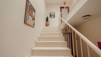 Un escalier avec des rampes blanches et des marches de couleur beige menant à un palier.