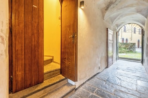 A stone staircase leading to a wooden door with a light fixture above it. - Historic Borgo Lake Como | Campidoglio 5 (Lenno)