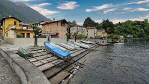 Un pueblo a orillas del lago con barcos amarrados a la orilla, rodeado de edificios tradicionales y montañas al fondo.