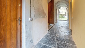 Un pasillo con puerta de madera, suelo de piedra y techo abovedado.