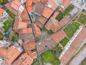 Une vue aérienne d’une zone urbaine densément peuplée, avec des toits recouverts de tuiles rouges, des rues étroites et de petits espaces verts.