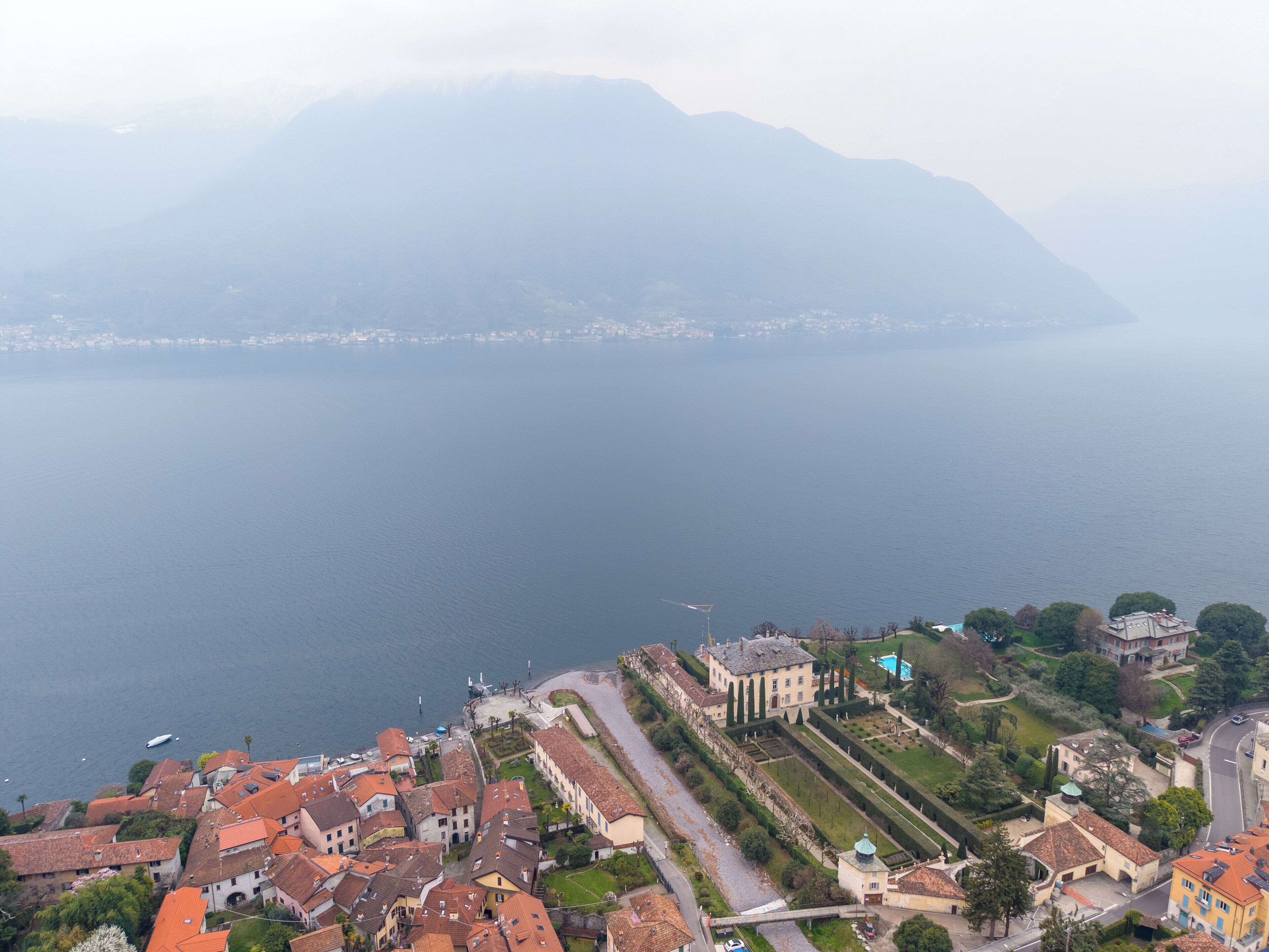 A coastal town with historic buildings, a marina, and a mountain backdrop.