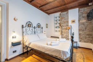 Une chambre à coucher avec un lit, des tables de chevet, un mur en pierre et un plafond en bois.