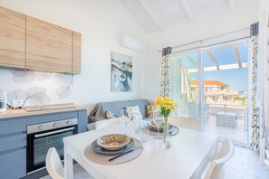 A modern kitchen with a dining area, a view through the glass door, and a ceiling fan. - Affittimoderni Castelsardo - Panorama (Castelsardo)