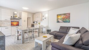 A modern living space with a dining area, a sofa, and a kitchen in the background. - The Amber - Tremezzo Lake Como (Tremezzo)