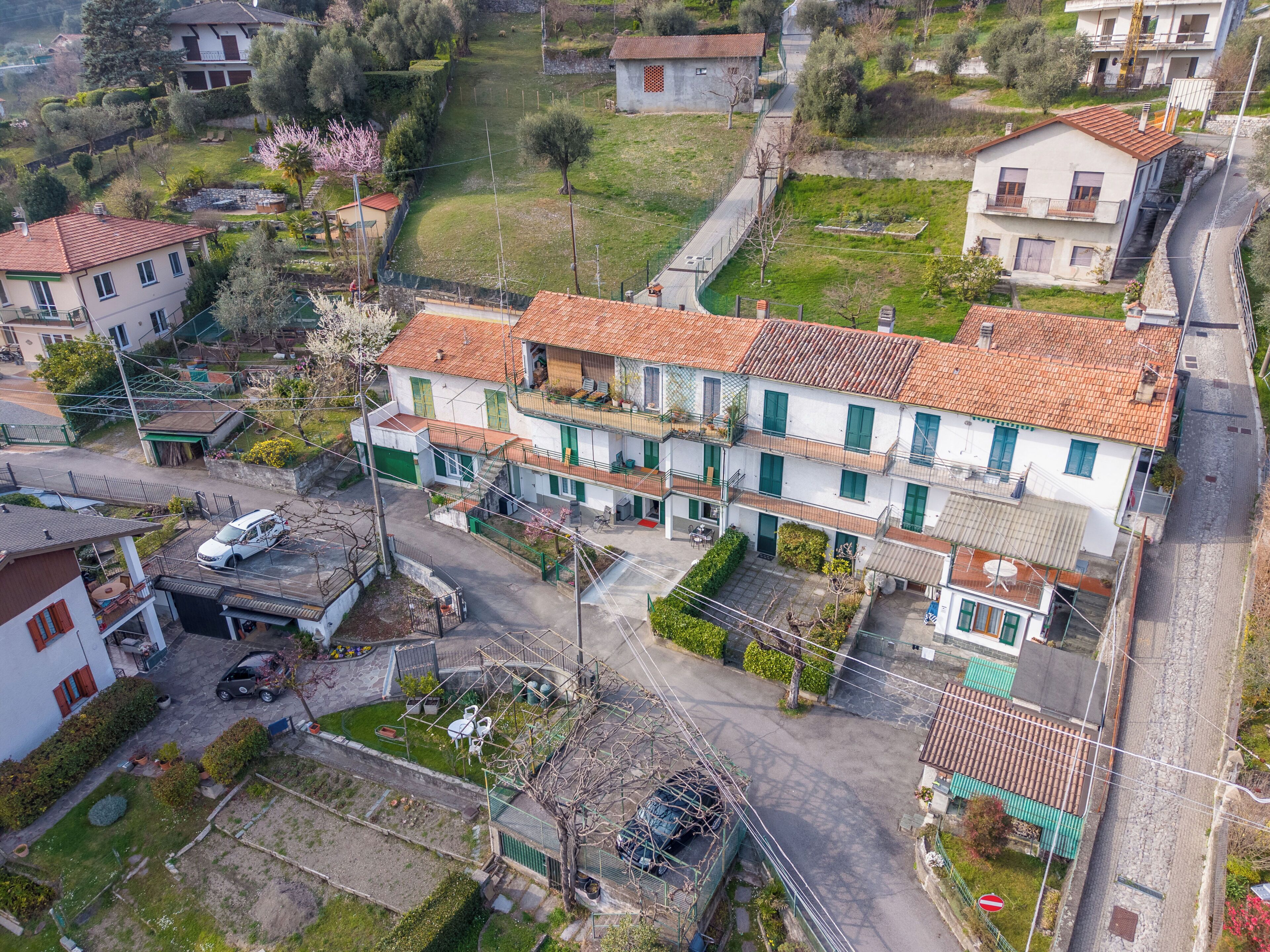 Un immeuble résidentiel à plusieurs étages, doté d’un toit recouvert de tuiles rouges, d’une cour intérieure et donnant sur la rue.