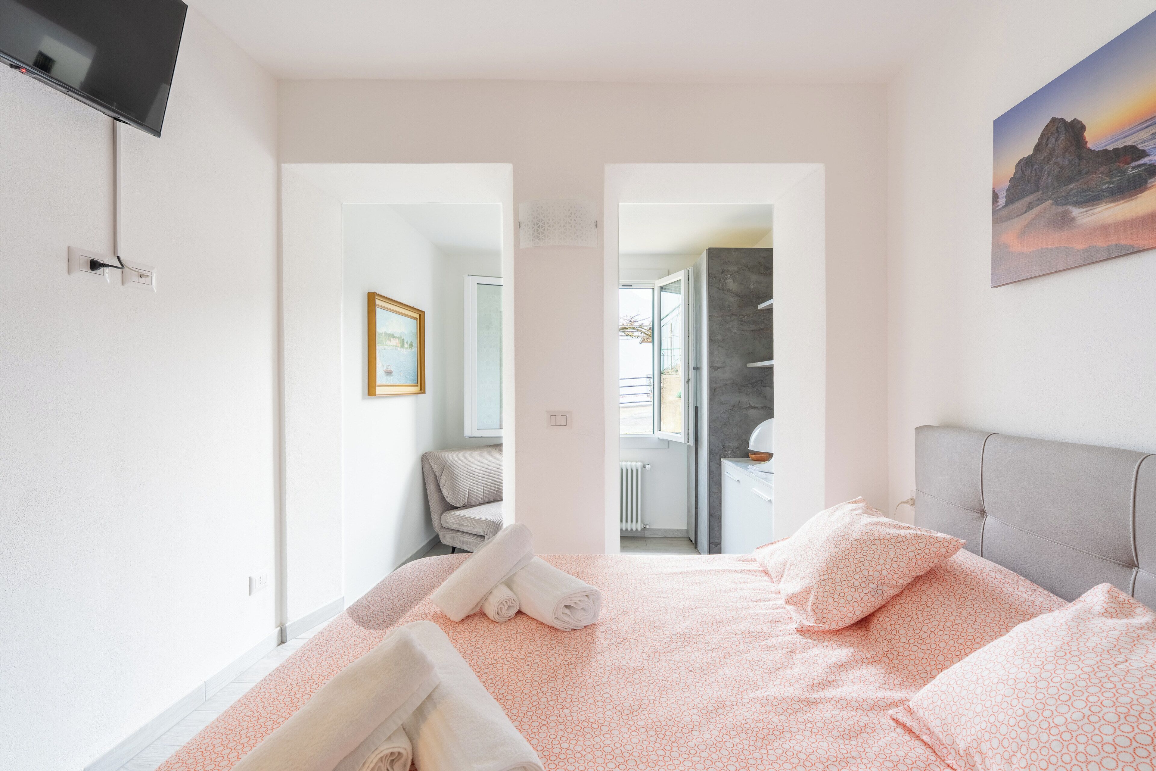 Una habitación de hotel moderna con una cama, un televisor, un cuadro y vistas al exterior.