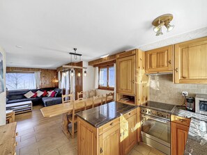 Eine geräumige Küche mit Holzausstattung, einer zentralen Kochinsel und einem Essbereich mit einer Couch und Stühlen.