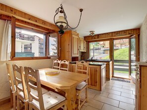 Ein Holzinterieur mit Esstisch, Stühlen und Küchenzeile.