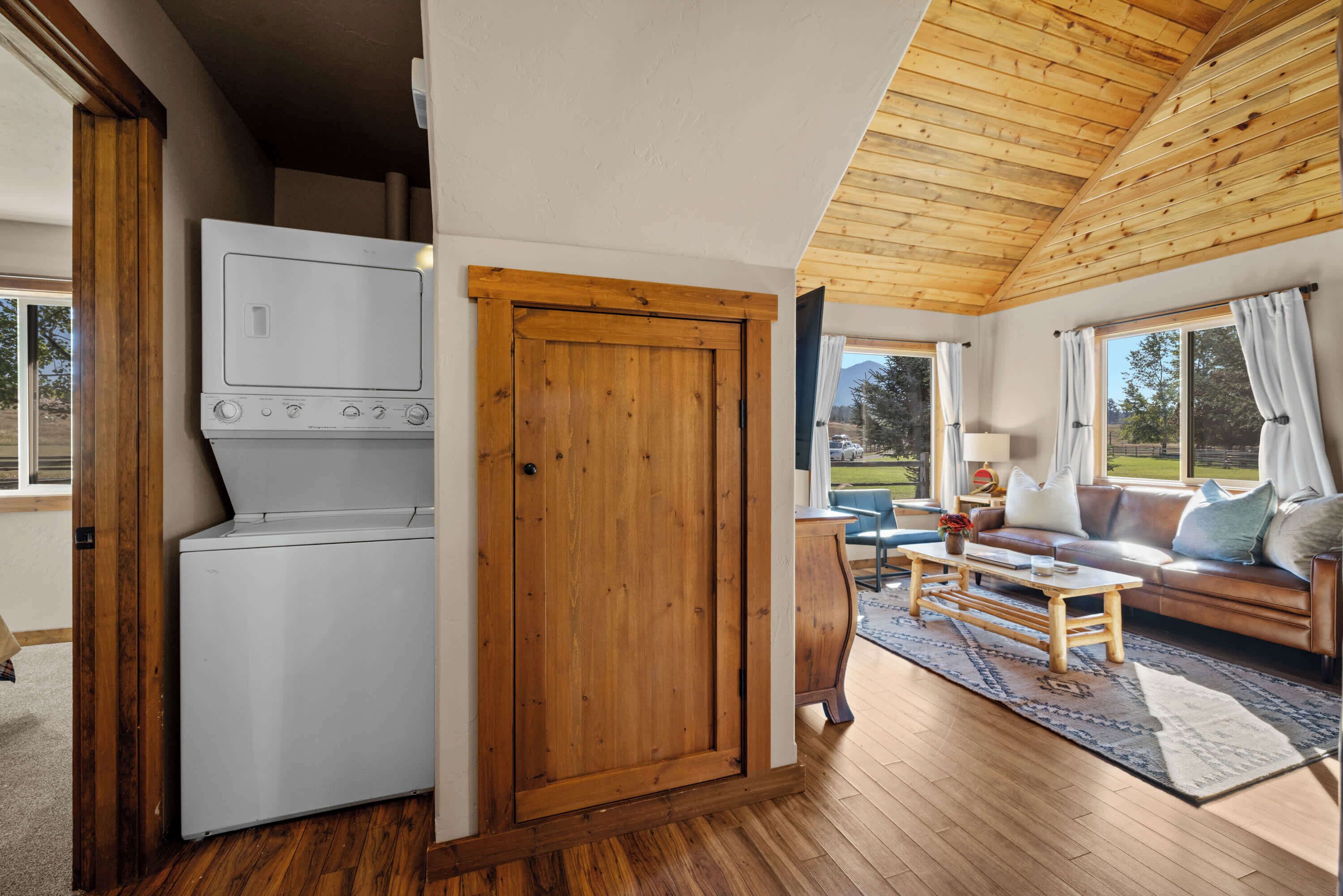 A compact living space with a wooden ceiling, a washing machine, a sofa, and a coffee table.