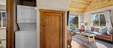 A compact living space with a wooden ceiling, a washing machine, a sofa, and a coffee table.