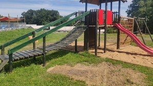 Un’area giochi con una struttura per arrampicata, uno scivolo e una casetta.