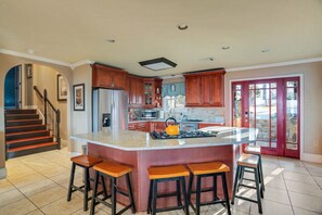 Uma cozinha com ilha central, banquetas, geladeira, micro-ondas e fogão.