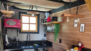 A compact kitchen with a microwave, sink, and bar stools.