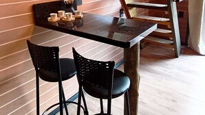 A dining area with a wooden table, two chairs, and a ladder against the wall.