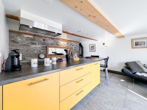 Eine moderne Küche mit Steinwand, einer Kaffeemaschine und einem Essbereich mit einer Couch.