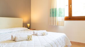 Een hotelkamer met een bed, een nachtkastje, een lamp en een raam met gordijnen.