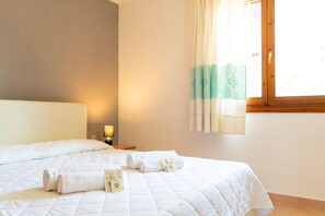 Ein Hotelzimmer mit Bett, Nachttisch, Lampe und einem fenster mit Vorhängen.
