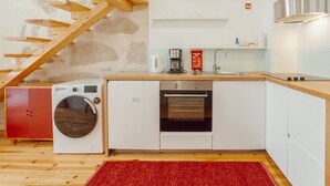 A modern kitchen with a washing machine, oven, and coffee maker. - Apartment  by Interhome (Porto)