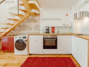 A modern kitchen with a washing machine, oven, and coffee maker. - Apartment  by Interhome (Porto)