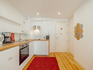 A compact kitchen with a built-in oven, a coffee machine, and a sink. - Apartment  by Interhome (Porto)