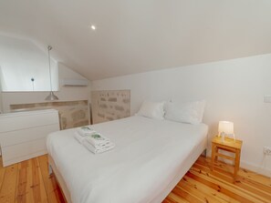 Un dormitorio con una cama, una mesita de noche de madera, un tocador blanco y una pared con diseño de piedra.