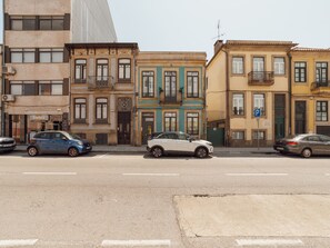 Una calle con edificios de varios pisos, coches aparcados y cielo despejado.