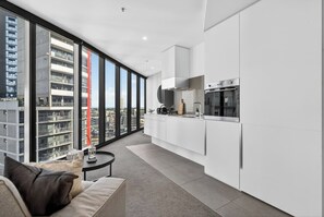 A modern kitchen with a large window, white cabinetry, and a built-in oven. - Luxury Sky-High Stay: Bay & Lake Views | Southbank (Southbank)