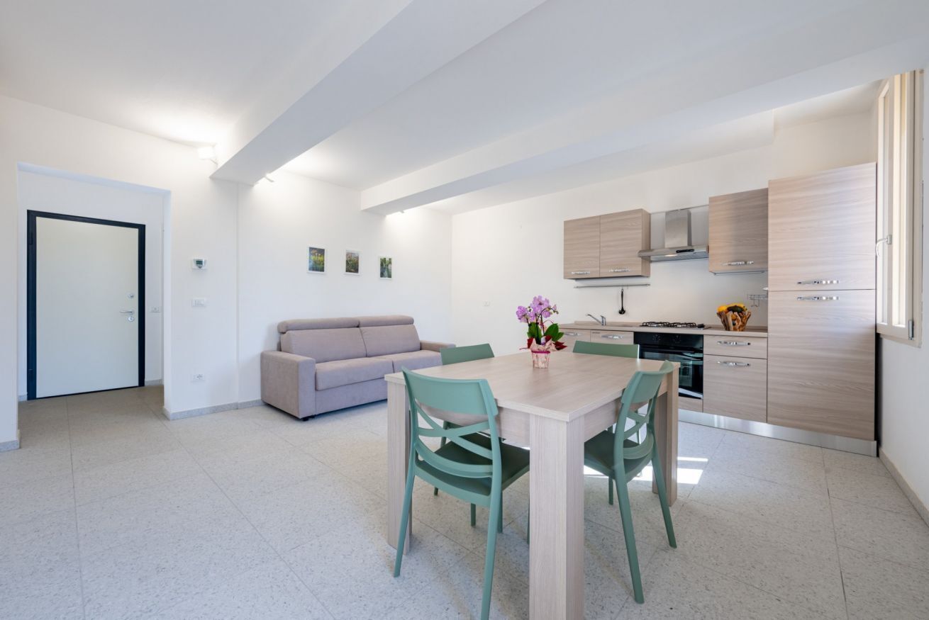 A modern kitchen with light wood cabinets, a built-in oven, and a stainless steel range hood.
