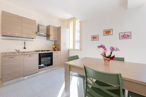 Una cucina moderna con mobili in legno chiaro, forno integrato e zona pranzo con tavolo e sedie.