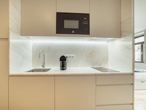 A modern kitchen with a built-in coffee maker, a digital clock, and a window. - Apartment  by Interhome (Porto)
