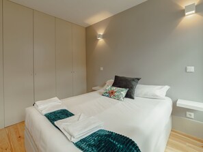 Ein Schlafzimmer mit einem Bett, Kissen, einer Decke, einer Wandleuchte und einem Kleiderschrank.