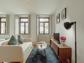 En moderne stue med sofa, sofabord, fjernsyn og lampe.