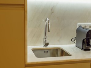 Eine moderne Küche mit einer Edelstahl-Spüle, einer integrierten Kaffeemaschine und einer Marmorarbeitsplatte.