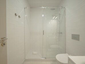 Ein modernes Badezimmer mit einer gläsernen Duschkabine, einer weißen Toilette und einem an der Wand befestigten Handtuchhalter.