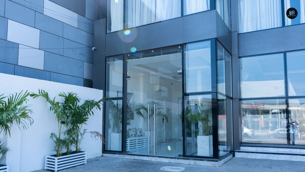 Een modern gebouw met grote glasramen, een verzorgde entree en potplanten.