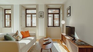 A modern living room with a sofa, a coffee table, a TV, and a bookshelf. - Apartment  by Interhome (Porto)