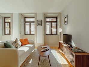 Ein modernes Wohnzimmer mit einer Couch, einem Couchtisch, einem Fernseher und einem Bücherregal.