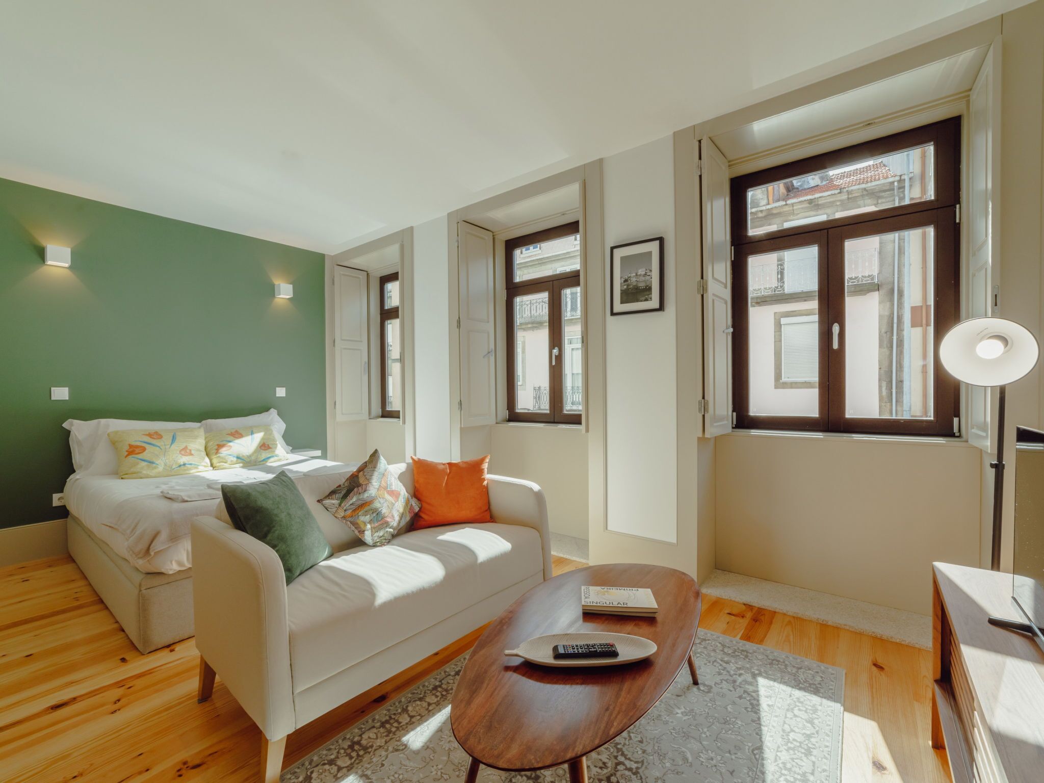 A modern living room with a white sofa, a wooden coffee table, and a green accent wall.