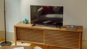 A television on a wooden stand with a remote control and a magazine on top. - Apartment  by Interhome (Porto)