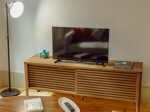 Ein Fernseher auf einem Holzständer mit Fernbedienung und einer Zeitschrift darauf.
