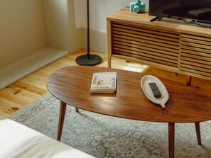 Et træsofa bord med en bog med titlen 'MURAKAMI PESSOA SINGULAR' og en fjernbetjening ovenpå.