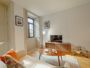 Una sala de estar moderna con sofá, mesa de centro, televisor y ventilador.
