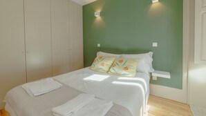 A bedroom with a bed, white linens, a green wall, and a wooden floor. - Apartment  by Interhome (Porto)
