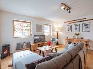 A cozy living room with a sofa, a TV, a fireplace, and a dining area with a table and chairs.