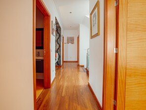 Ein Flur mit Holzdielen, einem Schrank mit roten Türen und einem gerahmten Bild an der Wand.