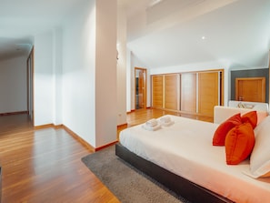 A modern hotel room with a large bed, a wooden wardrobe, and a view of the hallway. - POOL & CINEMA VILLA by VACATIONY by Interhome (Porto)