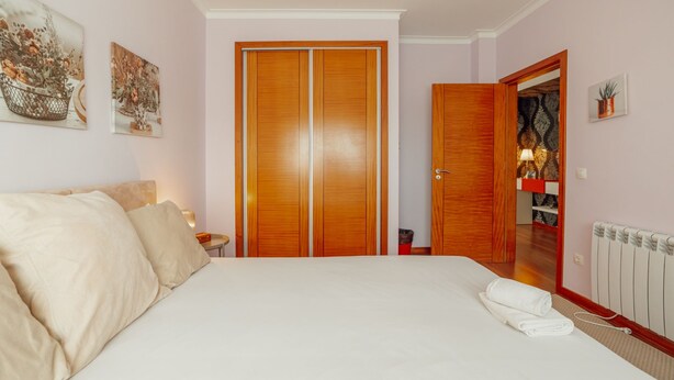 Ein Schlafzimmer mit einem großen Bett, einem Kleiderschrank, einem Spiegel und einer Heizung.