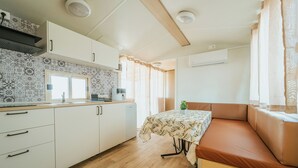 A compact kitchen with a dining area, a window, and a built-in bench. - Gotha Beach Srl - Casetta Lavanda (Ladispoli)